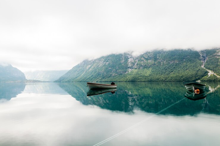 lonely-boats-calm-lake-with-misty-mountain-background_23-2148153617