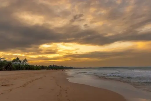 Serene sunset view over Bentota Beach and coastline in Sri Lanka, featuring golden skies and calm waves.