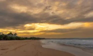 Serene sunset view over Bentota Beach and coastline in Sri Lanka, featuring golden skies and calm waves.